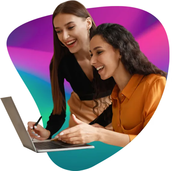 Two friends smiling as they look at a laptop together